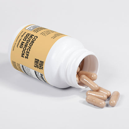 Supplement bottle with pills spilling out on a light gray background