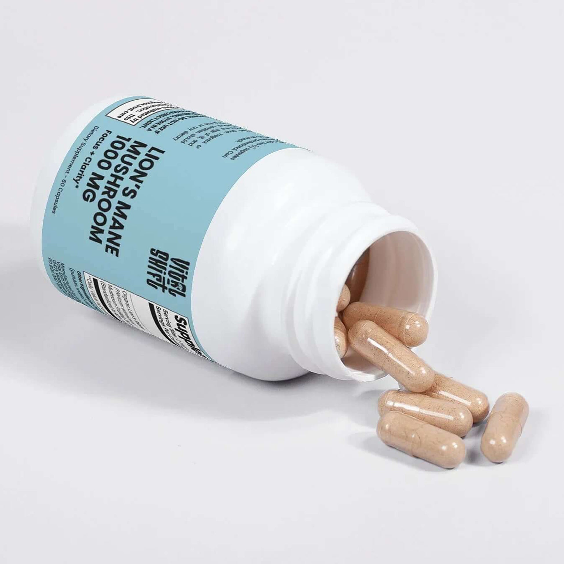 Bottle of Lion's Mane supplement with capsules spilling out on a light gray background