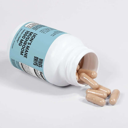 Bottle of Lion's Mane supplement with capsules spilling out on a light gray background